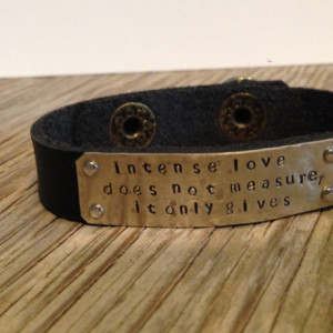 A riveted, 1/2 inch wide leather cuff bracelet with hand stamped brass distressed and embellished wording of your choice