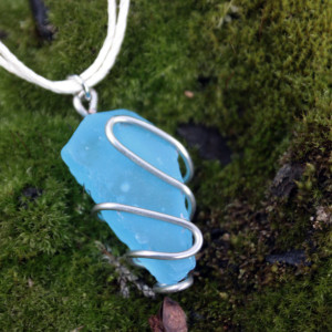 Blue sea glass pendant wrapped in thick wire on white hemp cord