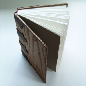 Handmade book, bound in wood, with open stitching onto leather bands.