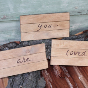 Wooden YOU ARE LOVED signs/plaques with wood burned lettering.