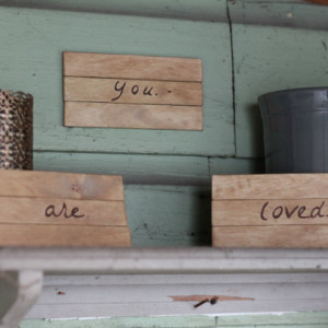 Wooden YOU ARE LOVED signs/plaques with wood burned lettering.