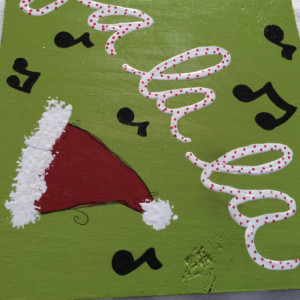 Whimsical Hand Painted Christmas Sign Decoration with Fa La La and Music Notes on Green Background with Santa Hat and Black & White Stripes